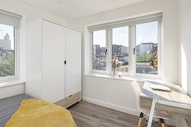 A bedroom in Old Vicarage with a large wardrobe, windows and a desk with a chair facing the opposite wall.